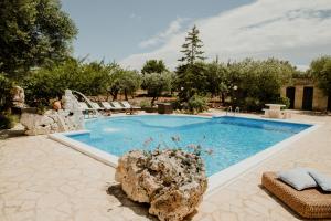 a swimming pool with a rock in a yard at Antica tenuta dei trulli in Alberobello