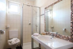 La salle de bains est pourvue d'un lavabo, d'une douche et de toilettes. dans l'établissement Pension zur Sonne, à Illmitz