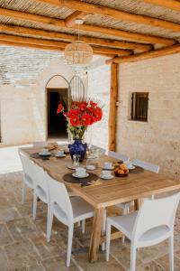 a wooden table with a vase of red flowers on it at Antica tenuta dei trulli in Alberobello