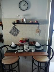 una mesa con dos sillas y un reloj en la pared en B&B Maria Rosaria Home, en San Marzano sul Sarno