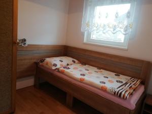 Una cama pequeña en una habitación con ventana. en Apartment chatky Aquaduo, en Liptovská Sielnica