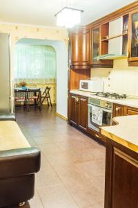 a kitchen with wooden cabinets and a dining room with a table at Рыбальская 8 in Kyiv