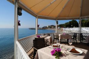 un restaurante con mesas y sillas y el océano en Appartamenti Villaggio Internazionale, en Albenga