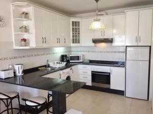 a kitchen with white cabinets and a black counter top at Apt Casa Mamen spacious with sea views in Puerto del Carmen