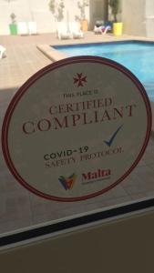 a sign that says the place is certified compliant at NSTS Campus Residence and Hostel in Msida