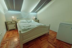een kleine slaapkamer met een bed en een houten vloer bij Pater Apartments and Rooms in Siófok