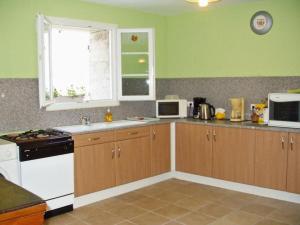 a kitchen with wooden cabinets and a white stove top oven at Les Coucous in Augerville-la-Rivière