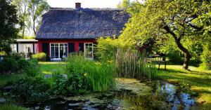 ein rotes Haus mit einem Teich davor in der Unterkunft Hof Garz in Poseritz