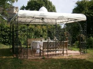 um gazebo com uma mesa e cadeiras por baixo em Les Gîtes du Chateau de la Morinière em Beaupréau