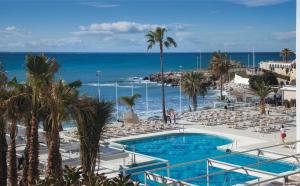 a resort with a pool and chairs and the ocean at Hotel Riu Monica - Adults Only in Nerja