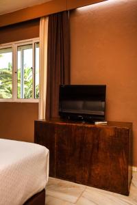 1 dormitorio con 1 cama y mesa con TV en Chillout Hotel Tres Mares en Tarifa