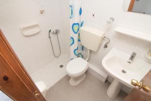 a white bathroom with a toilet and a sink at Anthea Apartments in Palaiochóra