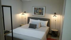 Un dormitorio con una cama blanca con dos lámparas. en Amelia's house, en Nauplia