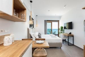 North Coast Seaside Suites في مدينة ريثيمنو: مطبخ وغرفة معيشة مع سرير وطاولة
