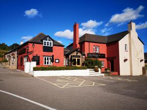 um edifício vermelho e branco num parque de estacionamento em Barn Owl Inn em Newton Abbot