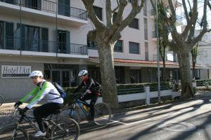 Dos personas en bicicleta por una calle frente a un edificio en Hotel L'Ast, en Banyoles