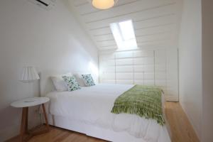 a white bedroom with a bed and a window at The Lookout Duplex - Bairro Alto in Lisbon