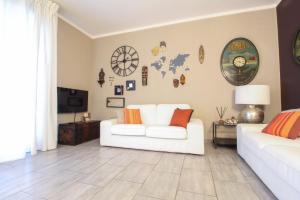 a living room with a white couch and clocks on the wall at La maison du monde in Bordighera