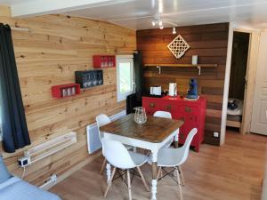 a dining room with wooden walls and a table and chairs at Le lodge sur pilotis in Fichous-Riumayou