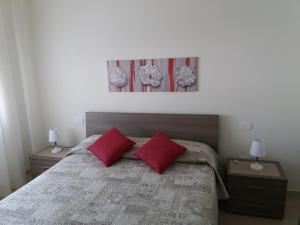 a bedroom with a bed with two red pillows at Casa Ely in Sottomarina