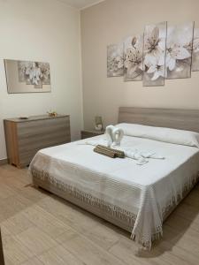 a bedroom with a bed with white sheets and paintings at Casa Vacanze Magistro in Patti +17 photos