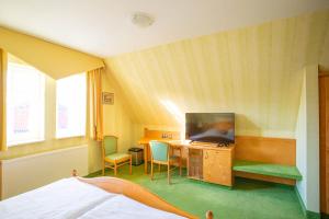 エシュヴェーゲにあるHotel-Pension Eschwegeのベッド、テレビ、デスクが備わる客室です。