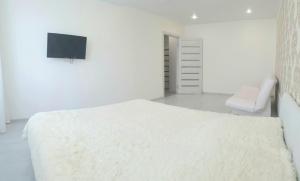 a white bedroom with a bed and a tv at Apartment on Karla - Libknekhta in Yaroslavl