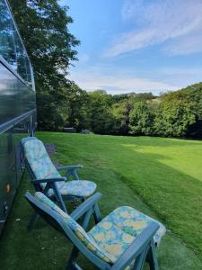 two chairs sitting on the grass next to a bus at Fosfelle Glamping in Hartland