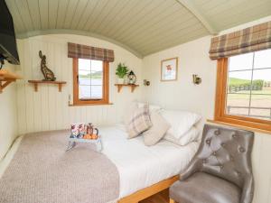 a small bedroom with a bed and a chair at Ivy's Way in Rhayader