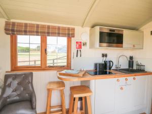a kitchen with a sink and a counter with stools at Ivy's Way in Rhayader