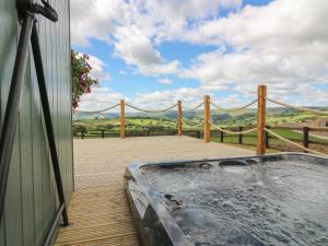 a hot tub on a deck with a fence at Ivy's Way in Rhayader