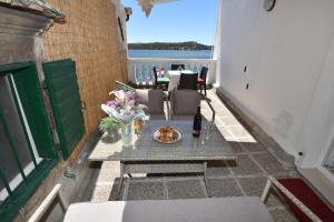 a patio with a table with a bottle of wine and flowers at Apartmani Rina in Šibenik