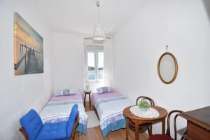 a room with two beds and a table and a mirror at Apartmani Rina in Šibenik