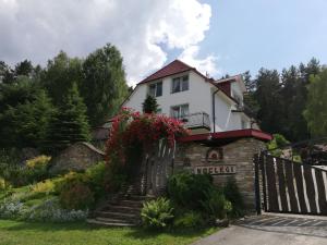 a white house with a gate and flowers at Noclegi Panorama in Ustrzyki Dolne
