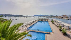 a swimming pool with umbrellas and a body of water at Hoposa Daina- Adults Only in Port de Pollensa