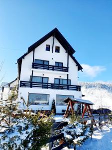 a large white house with snow on the ground at Pensiunea Soarelui in Fundata