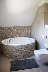 a bathroom with a tub and a toilet and a sink at Apartmány VÍNO HRUŠKA Pardubice in Pardubice