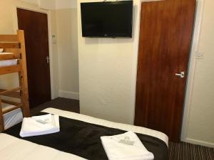 a hotel room with a television and two towels on a bed at The Feathers Hotel in Blackpool