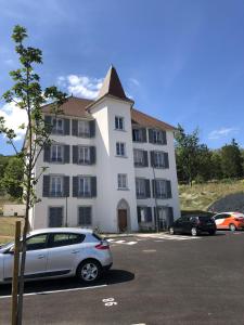 un gran edificio blanco con un coche aparcado en un aparcamiento en Domitys - Le Manoir en Pérignat-lès-Sarliève