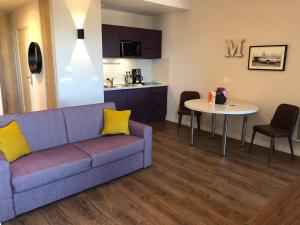 a living room with a couch and a table at Domitys - Le Manoir in Pérignat-lès-Sarliève