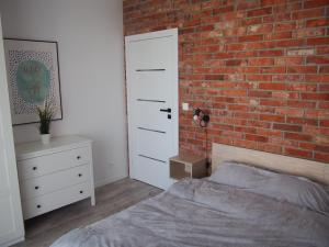 a bedroom with a brick wall and a bed and a white door at Nadmorska Ostoja z prywatnym miejscem postojowym in Pogórze