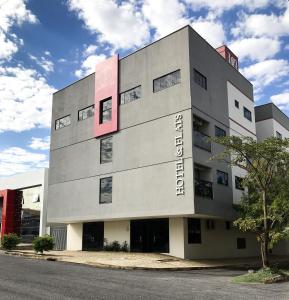 a building with a pink sign on the side of it at 103 Hotel & Flats in Palmas