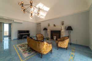 a living room with a fireplace and chairs and a chandelier at Villa Ortensia D'Avalos in Alvignano