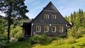 a black and white house in the middle of a field at Chalupa Janov nad Nisou 1064 in Janov nad Nisou