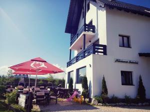 a building with an umbrella and a table and chairs at Pensiunea Soarelui in Fundata