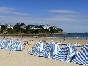 un groupe de parasols rayés bleus et blancs sur une plage dans l'établissement Gite es Omnes, à Pleurtuit