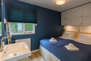 een blauwe slaapkamer met een bed en een wastafel bij Welcome in - Vakantiewoning met zonnige tuin, dichtbij zee en strand I Noordendolfer 2-49 in Zoutelande