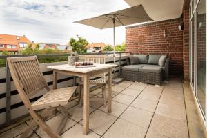 einen Tisch und Stühle auf einem Balkon mit Sonnenschirm in der Unterkunft DünePur in Norderney