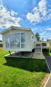 ein weißes Haus mit einer Veranda auf einem Rasen in der Unterkunft RJ Luxury Caravan Hire With Hot Tub in Tattershall