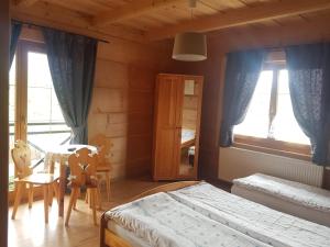 コシチェリスコにあるDworek na Klinieのベッドルーム1室(ベッド2台、テーブル、窓付)